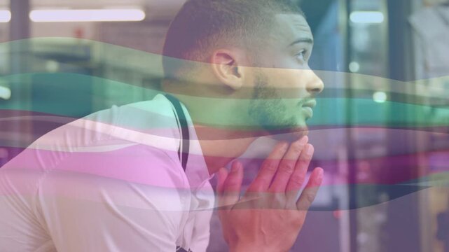 Man in business lobby covering face then clasping hands, lifting head seeking focus with color band