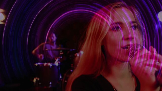 Lead singer lifting mic and singing to perform music, purple or pink rings swirling around singer