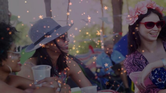 Three women talking at park tech event, left woman raising cup, sparking laughter, stars overlaying
