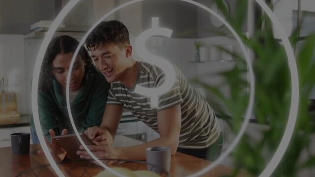 Pair leaning over kitchen island tapping tablet, activating currency overlay, reviewing finances