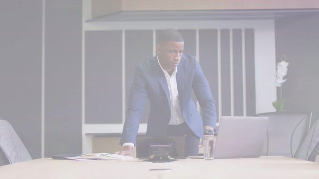 Man in blazer shifting toward laptop, grabbing tumbler, adjusting jacket, preparing business
