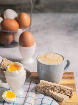 Soft boiled egg in egg cup with coffee, simple breakfast with bread