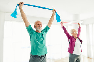 Fototapeta premium Senior couple exercise stretching and exercising with resistance band at home, health care and rehabalitation recovery concept