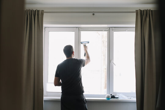 Man washing and cleaning window at home. Housework and housekeeping, home hygiene