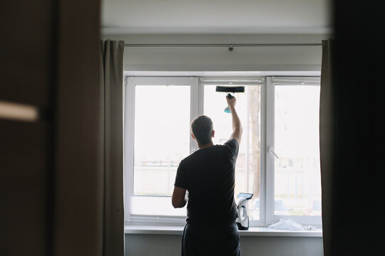 Man washing and cleaning window at home. Housework and housekeeping, home hygiene