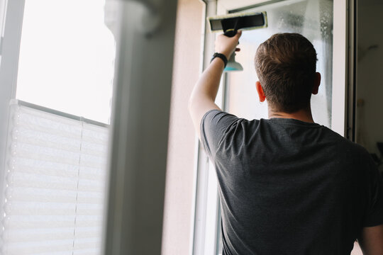 Man washing and cleaning window at home. Housework and housekeeping, home hygiene