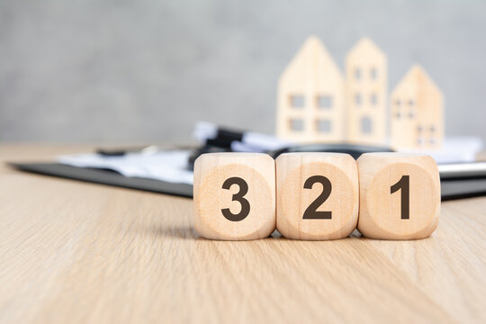 Wooden blocks with 3 2 1 numbers blurred clipboard and house models.