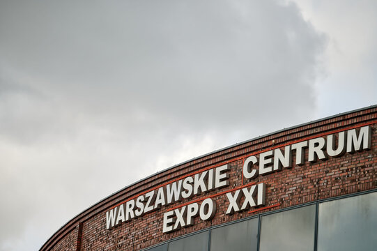 Exterior of Warszawskie Centrum Expo XXI building, showing the bold white letters on a brick facade under a cloudy sky in Warsaw, Poland