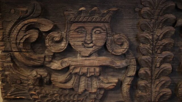 A wooden carving of a person grasping a bird in their hands