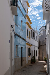 Fototapeta premium Narrow street in Olhao with traditional blue tiled building facade and white houses