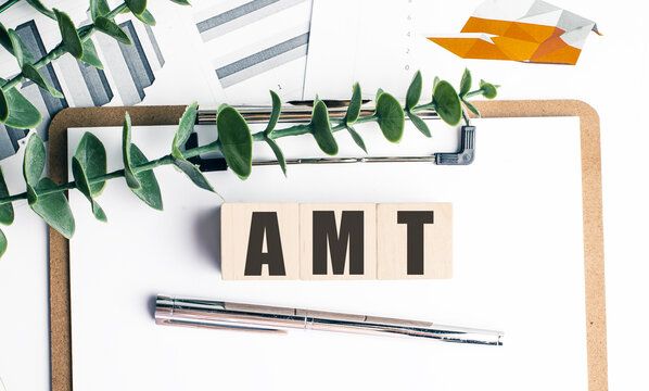 Amt concept with wooden blocks clipboard financial charts and pen on desk alternative minimum tax finance background
