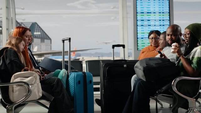 Hearing flight announcement, diversity and tourists in airport standing up from chairs. Queuing up, concept of organized travel flow and multiracial people ready for departure go to boarding gate