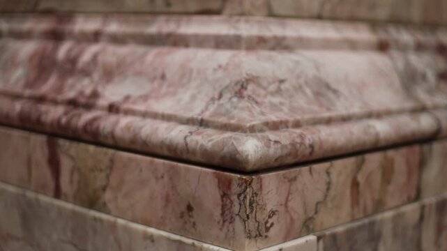 A close-up shot of a pink marble column with intricate details and patterns