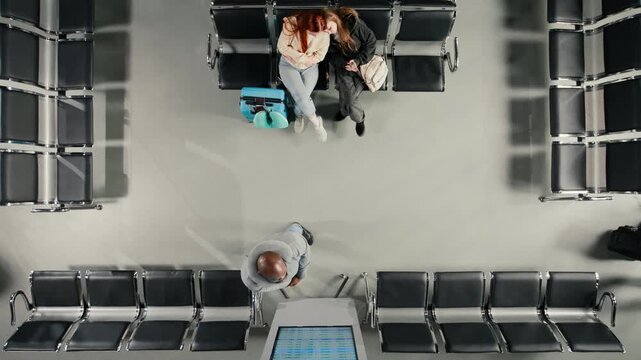 Checking departure board, timetable and airport with friends traveling together, top down view. Catching plane for holiday trips, FIDS screen schedule and travel buddies, high angle shot
