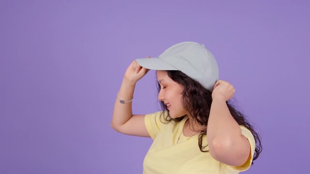 Beautiful young woman smiling while putting on a baseball cap