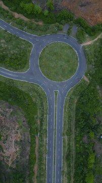 Roundabout Amid Trees. Aerial Perspective Of Lush Green Circular Junction. Elevated Perspective Highlighting Dense Forest Surrounding Circular Traffic Circle With Natural Buffer Zones