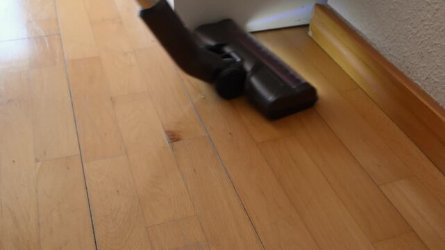 Cordless stick vacuum cleaner cleaning wooden floor
