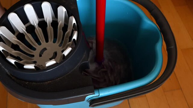 Woman wringing out a spin mop using a wringer bucket