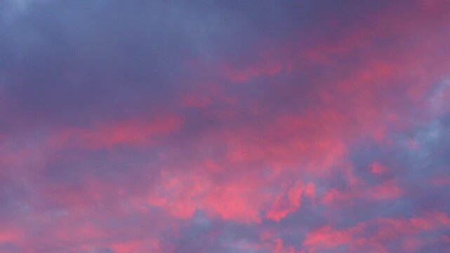 Majestic real sunrise sundown sky background with gentle colorful clouds. Panorama of cloudscape at sunset with vivid and dreamy colors on sky. A vibrant sunset sky painted in hues of orange pink.  
