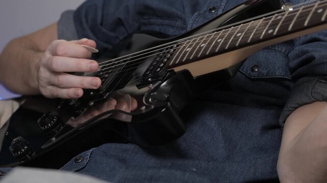 play electric guitar close up fingers slide over strings of electric guitar