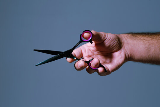 Barber holding scissors. Barbershop interior background. Haircut tools and grooming. Professional barber scissors for men.