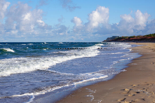 Scenic sandy beach Baltic sea with sea waves and clouds. Dziwnow, Poland