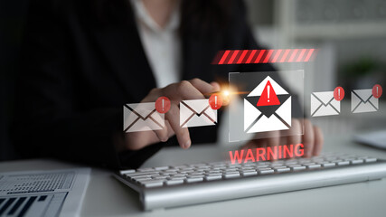 Plakat A business professional uses a keyboard to monitor an email interface filled with alert notifications indicating potential cybersecurity threats and warnings. Gantry