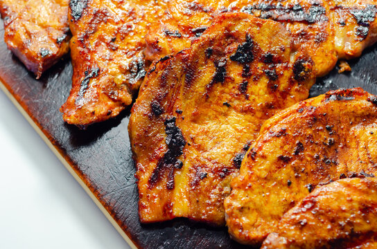 Grilled pork chops sizzle on a dark cutting board
