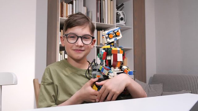 Young boy with round glasses smiling at camera while proudly holding a colorful toy brick robot, inspiring stem learning, creativity, engineering play and imaginative childhood exploration