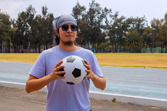 Cool Hispanic Young Man holding Soccer Ball Outdoors
