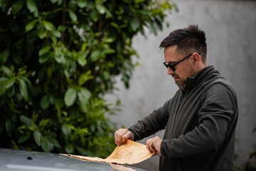 Man opening brown envelope outdoors receiving mail © Zoran Jesic