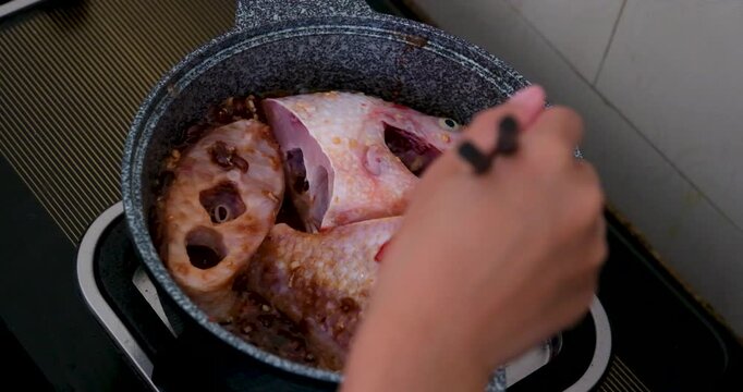 Vietnamese red fish cooking in gray pan with chili garlic and salt simmering on gas stove showing traditional soup preparation step by step
