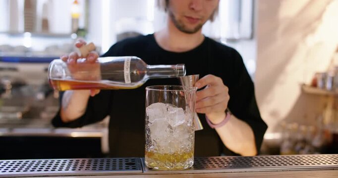 Mixologist work. Making cocktail. Bartender pouring sweet aroma color syrup from metal jigger to glass. Flavored refreshing drink.