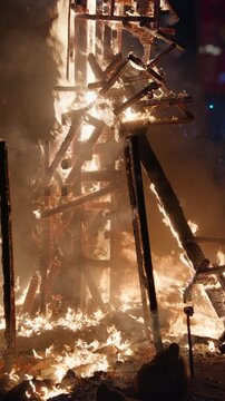 Massive burning falla structure collapsing in intense flame during traditional crema ceremony of Fallas festival in Valencia, glowing wooden framework disintegrating amid ember
