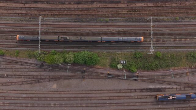 Top down aerial drone view of a train moving along railway tracks. Industrial rail transport, logistics and infrastructure concept.