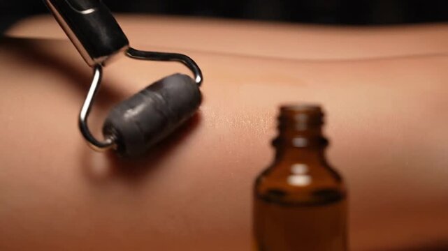 Close-Up Of Facial Roller Gliding Over Skin With Essential Oil Bottle In Background, Perfect For Skincare And Beauty Concepts
