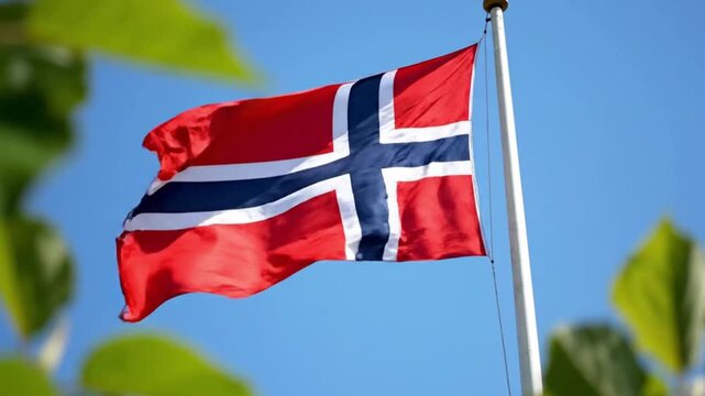Norwegian flag waving on a flagpole against a clear blue sky