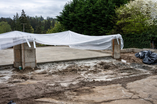 New residential house foundation construction, concrete slab poured and covered with plastic sheet for drying and curing
