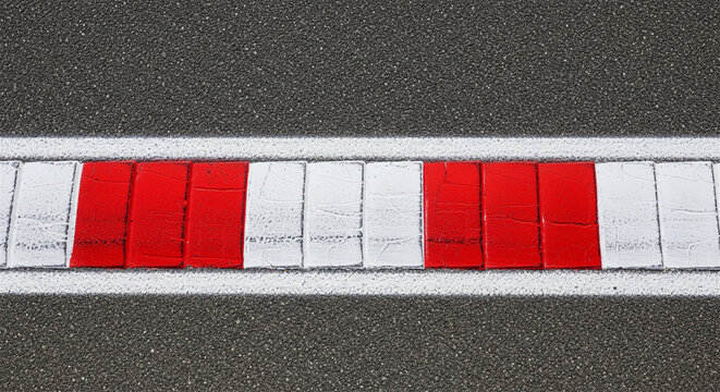 Racing track curb with red and white stripes, asphalt road surface with painted rumble strip, motorsport circuit boundary line