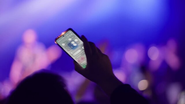 Crowd silhouette with raised arms visible against blurred purple and pink bokeh concert lights, very shallow focus dreamy feel