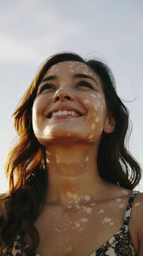 Young woman smiling with dappled sunlight on face looking up outdoors medium shot