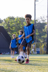 Fototapeta premium Group of boys and girls enjoy to practice to play soccer together in football field with day light and they look happy to exercise to get good health.