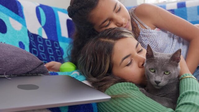 Mother and daughter affectionately cuddling pet cat