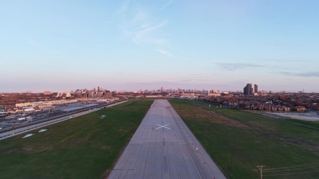 A cinematic drone shot moving forward along the abandoned runway of the closed Downsview Airport (YZD), revealing the Toronto city skyline and the CN Tower on the distant sunset horizon
