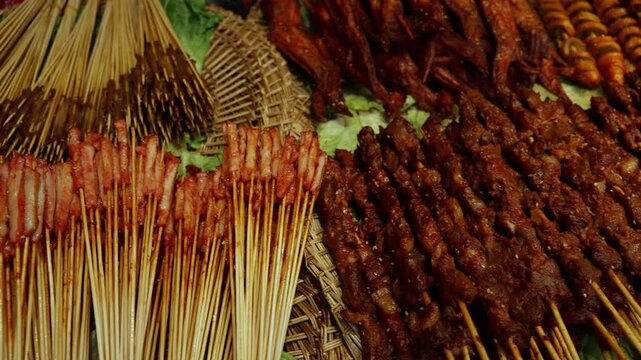 Street food skewers assortment in Chinese night market with camera moving across grilled meat snacks and traditional cuisine close up video still