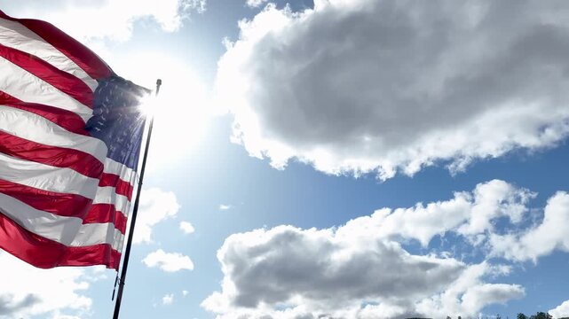 US Flag Waving in the Breeze with Blue Sky and White Clouds