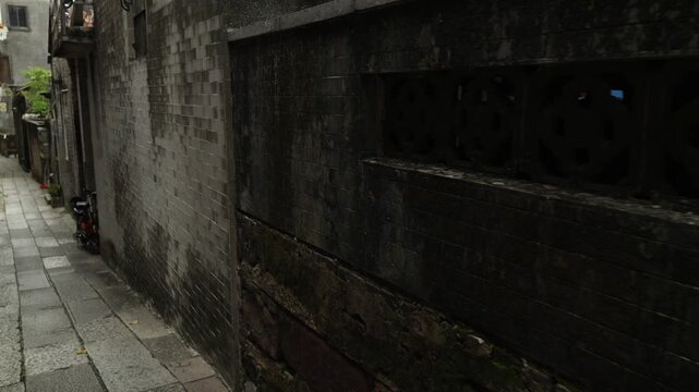 Walking through narrow Chinese alley with dark brick walls and old residential buildings urban passage perspective cinematic video still Guangzhou China