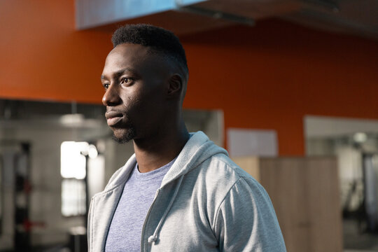 Gym-goer turning head left after offscreen clatter, checking mirror and gym equipment arrangement