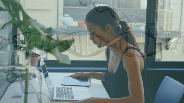 Woman checking phone then placing it beside laptop and typing while DNA helix overlay across frame