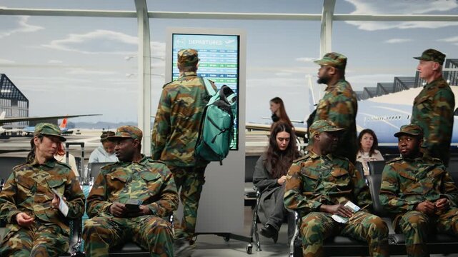 Looking at flight status, display timetable and army men in airport departure lounge. Waiting for plane arrival, electronic departure board and military squad reading schedule, camera A